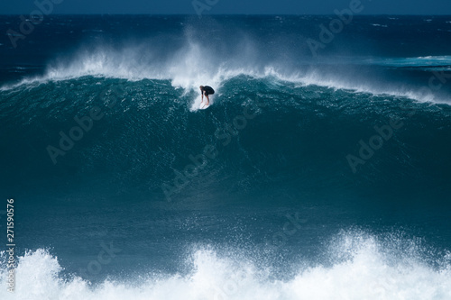 Surfer rides giant wave at the famous Banzai Pipeline surf spot located on the North Shore of Oahu in Hawaii