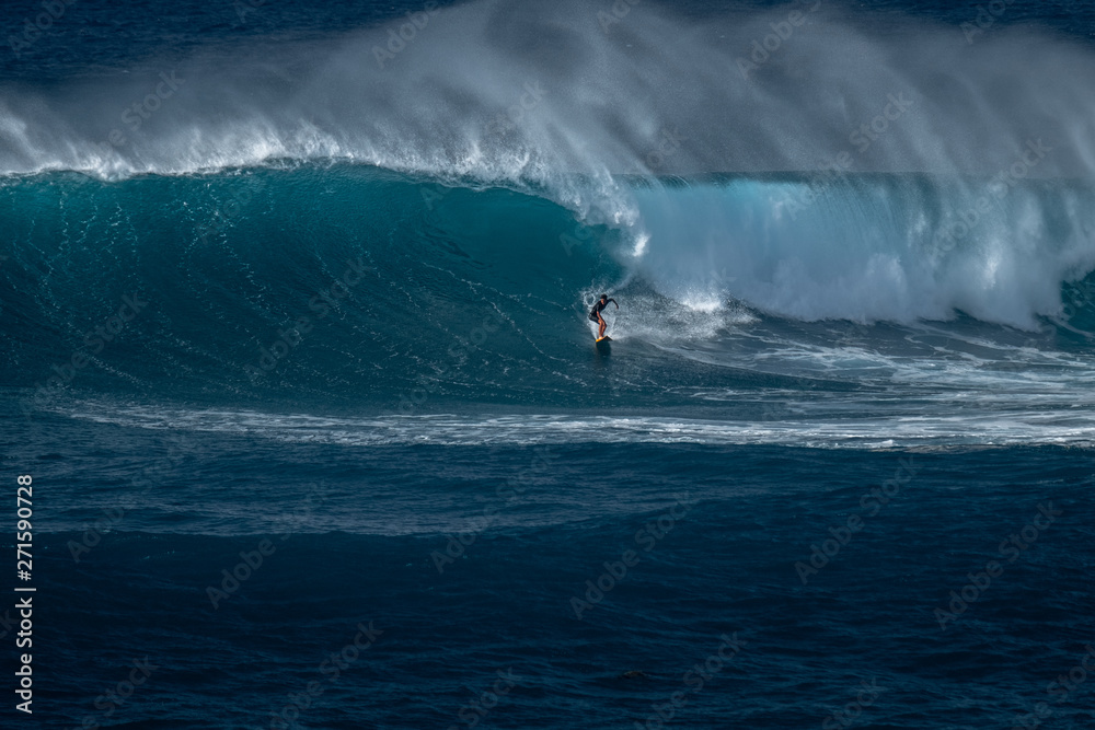 Surfer rides furious wave at the famous Waimea Bay surf spot located on the North Shore of Oahu in Hawaii