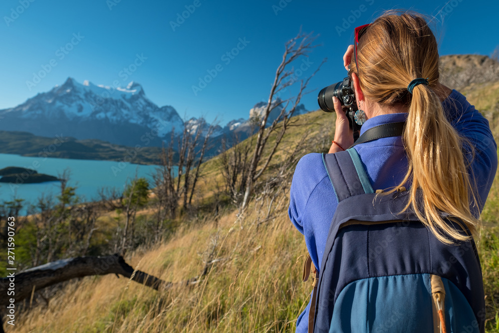 Woman photographer takes photo of the mountains in Torres del Paine National Park in Chile