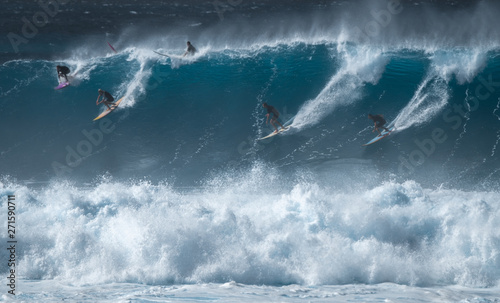 Four surfers share the giant wave at the famous Waimea Bay surf spot located on the North Shore of Oahu in Hawaii