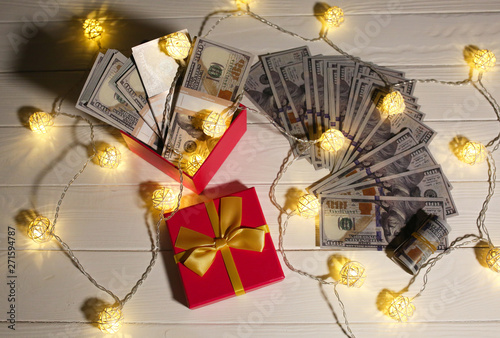Money as a gift. Dollars with present box and lights. Christmas or birthday day. Sale concept shopping.
