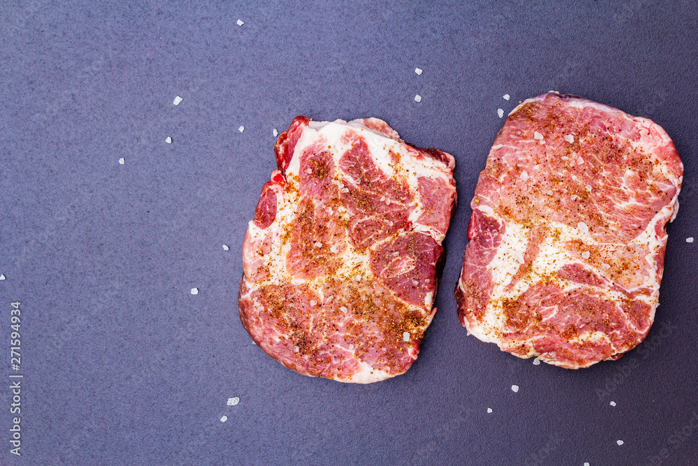 Organic raw pork steak, marinated in dry spices, with sea salt