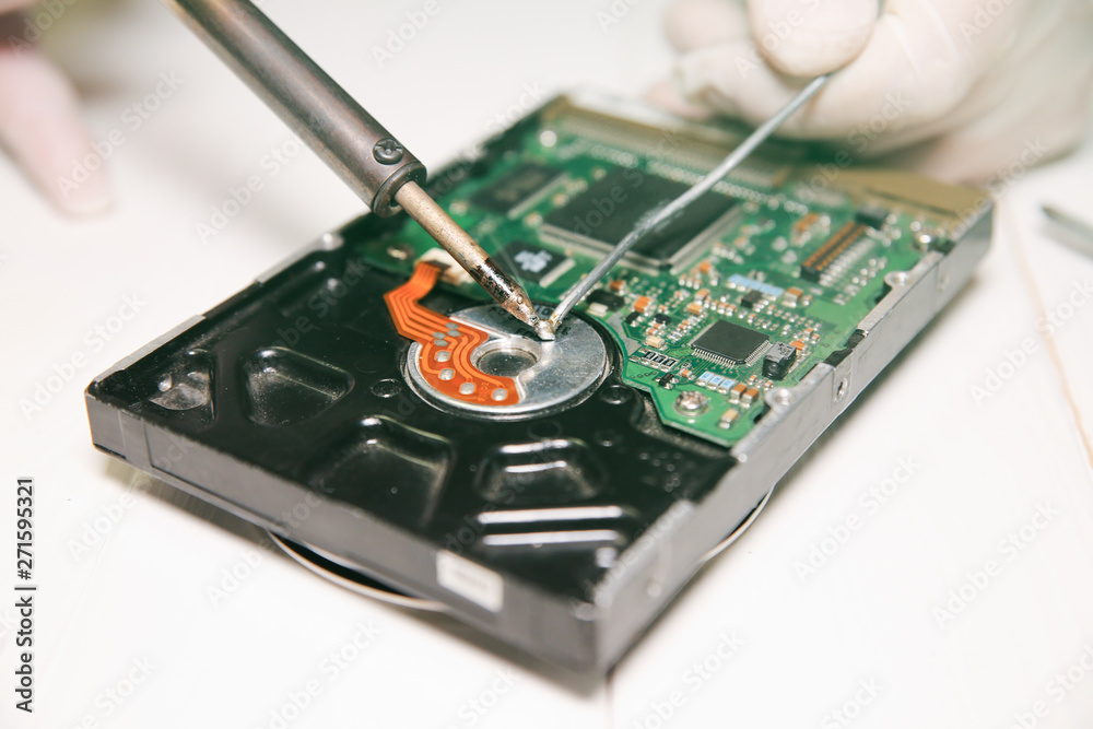 Man repairing hard disk. Inside details of the old personal computer. Broken PC. Soldering iron in hands. Man repairing hard disk. Inside details of the old personal computer. Broken PC. Soldering iron in hands.