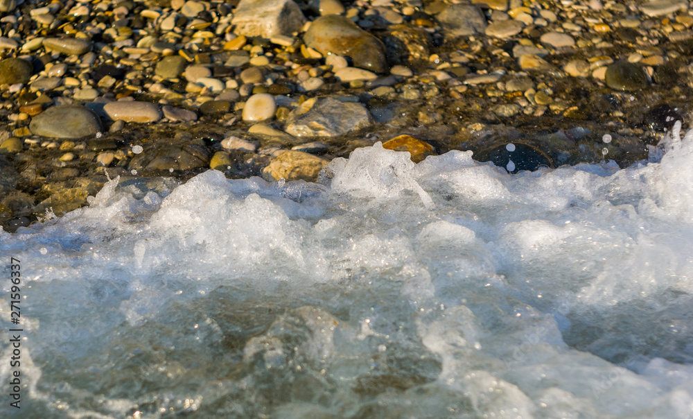 Fototapeta premium pebble stones on the sea beach, the rolling waves of the sea with foam