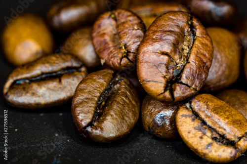 Brown roasted coffee beans on black background, close up, macro