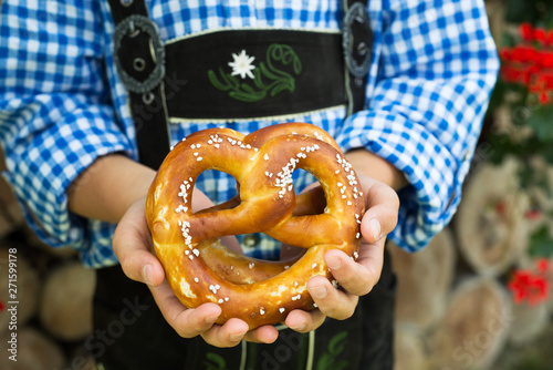 Close up of pretzel in the boy hands wearing a traditional bavarian clothes during Oktoberfest in Germany .