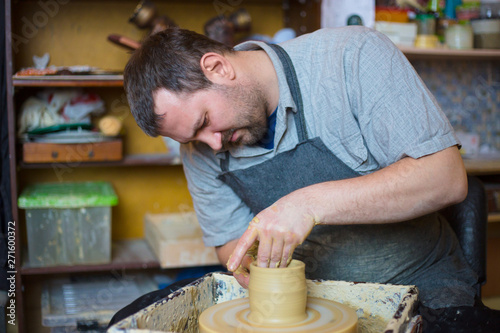 Professional male potter working with clay on potter's wheel