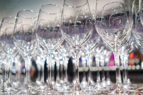 Several rows clear, clean glasses for wine and champagne on counter prepared for drinks.