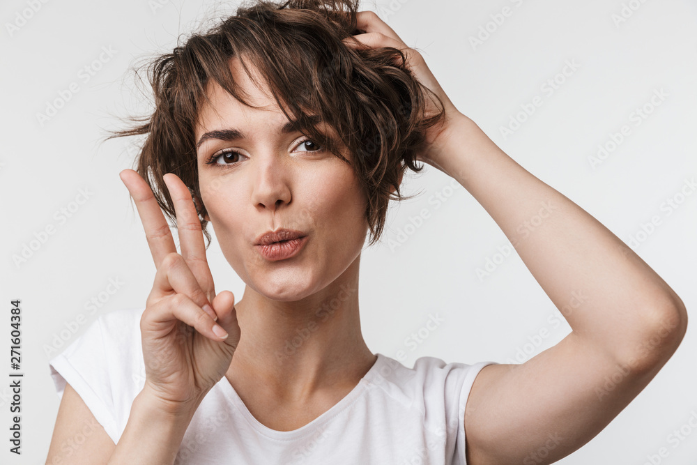 Fototapeta premium Excited happy woman posing isolated over white wall background showing peace gesture.