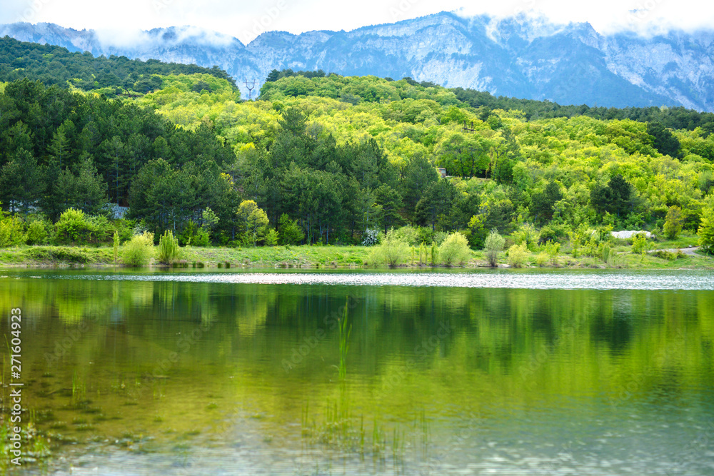 Scenic view of a mountain lake, with reflection on the water of the sky and mountains. Spring time.