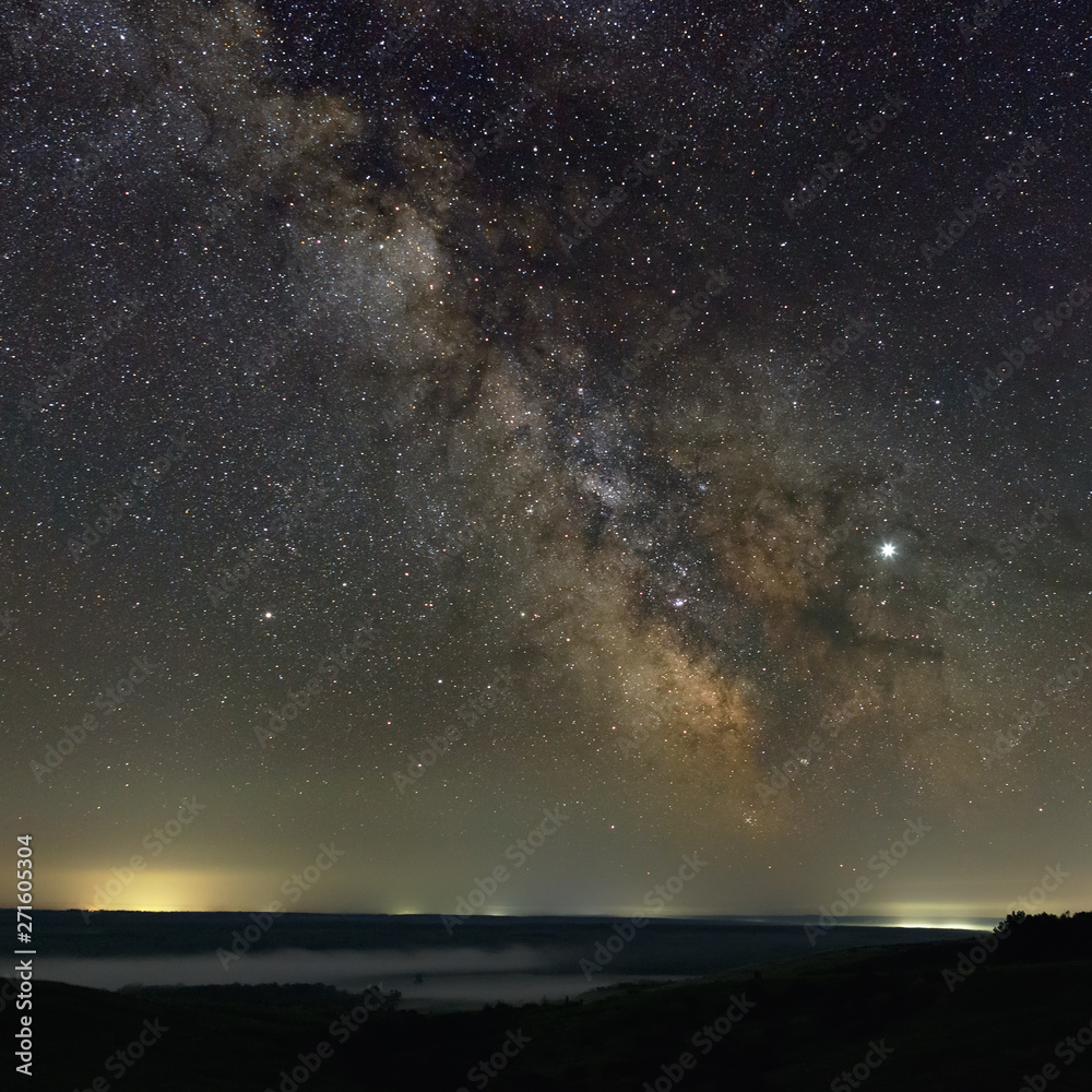 Fototapeta premium Stars in the sky at night. Bright milky way over the horizon with fog. Photographed with a long exposure.