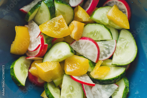 Fresh summer salad with radishes, cucumbers and yellow peppers.