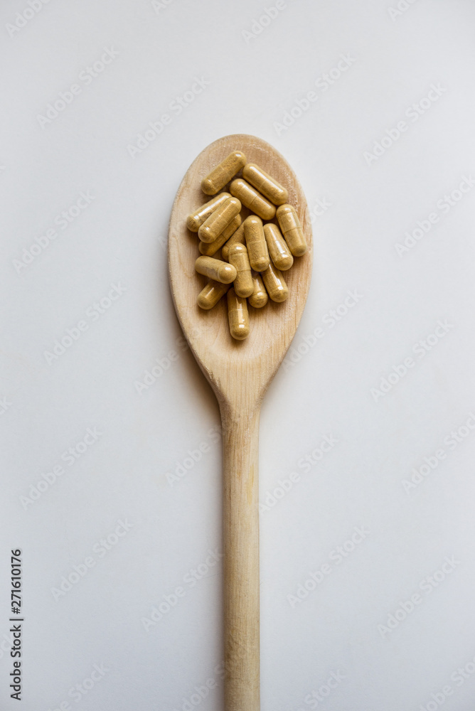 Wooden spoon containing capsules of food supplement Wooden spoon containing capsules of food supplement