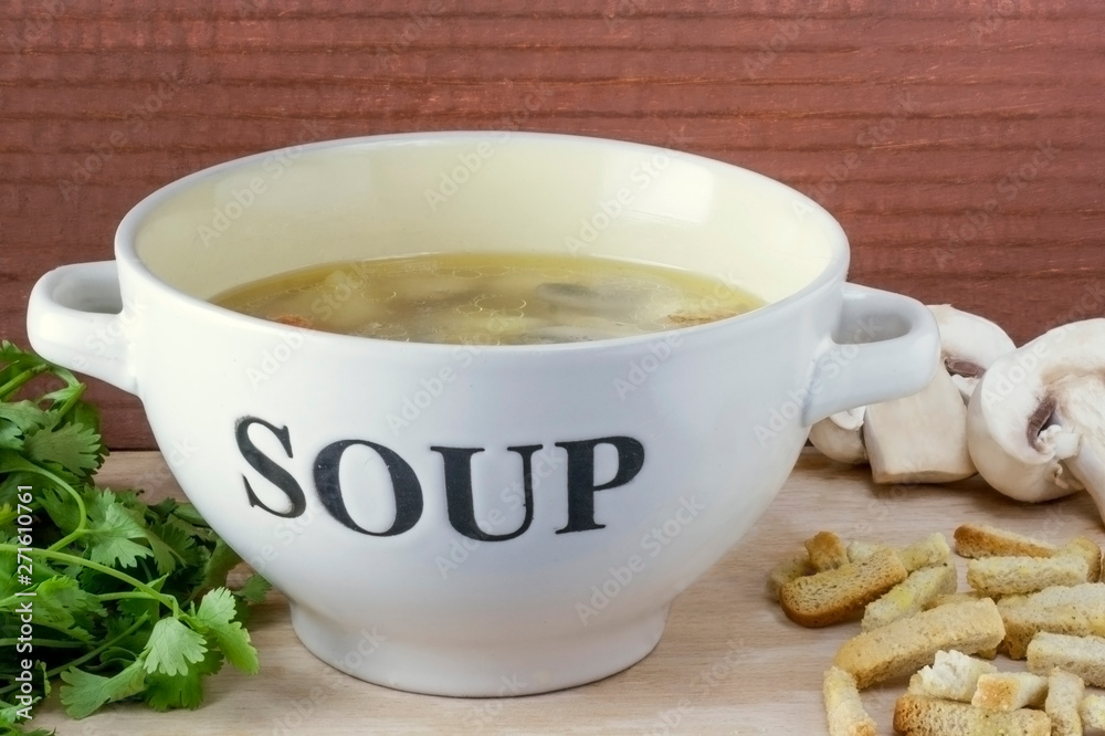 Bowl of chicken broth with mushrooms mushrooms close-up on a light wooden background Bowl of chicken broth with mushrooms mushrooms close-up on a light wooden background