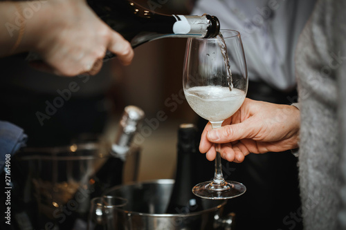 Wine tasting. Champagne is poured into a glass to the visitor. Close up.