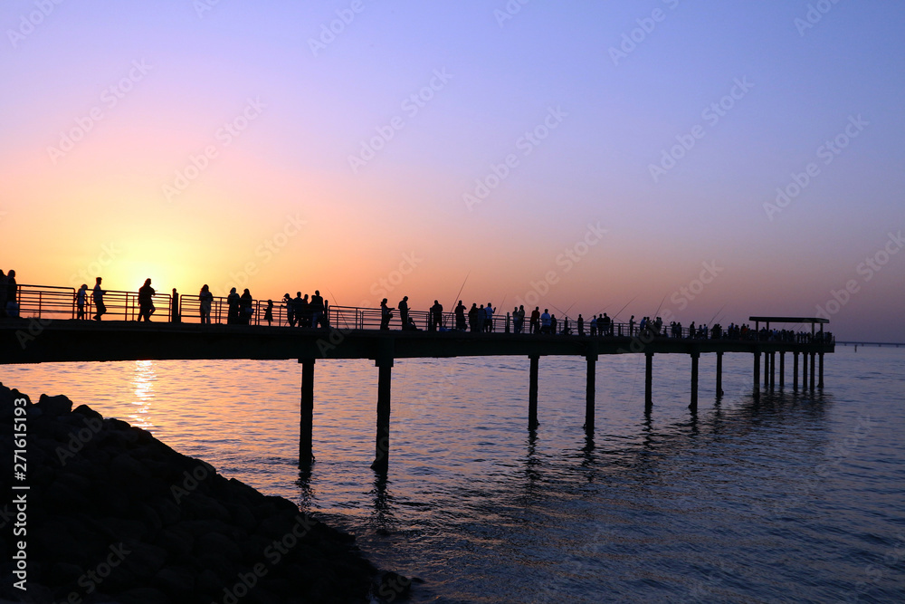 People silhouetted on a pier at sunset