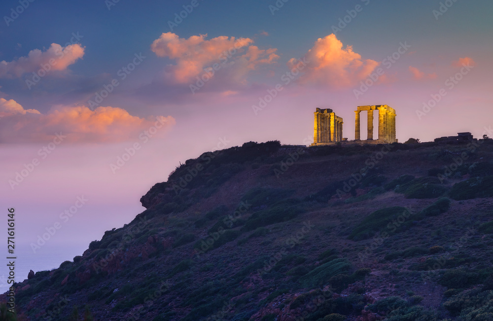 view to golden columns of greek temple on the cape under beautiful clouds in sunset time