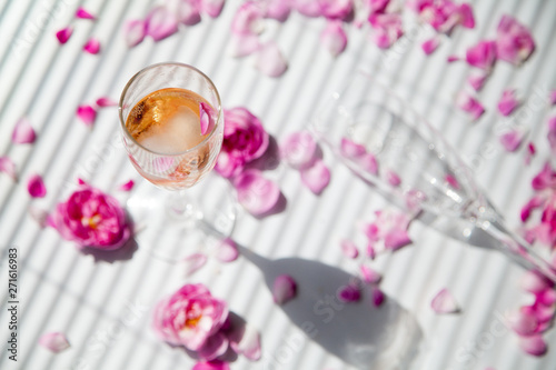 glasses of pink sparkling wine and glass on a white background with pink roses