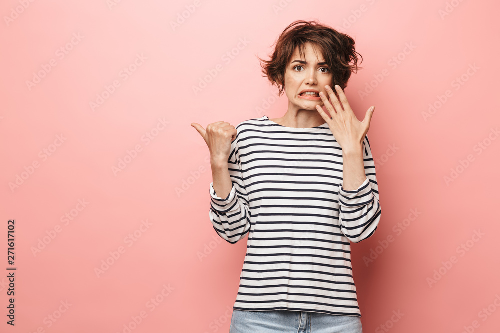 Confused shocked beautiful woman posing isolated over pink wall background pointing. Confused shocked beautiful woman posing isolated over pink wall background pointing.