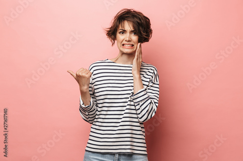 Fotografia Confused shocked beautiful woman posing isolated over pink wall background pointing