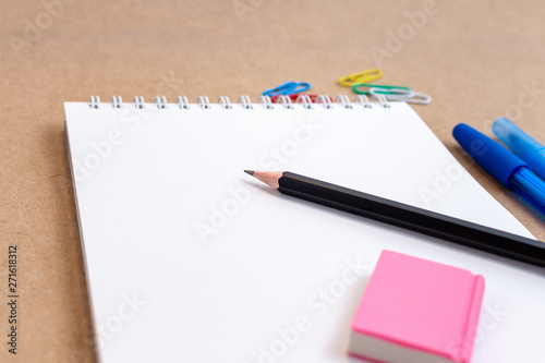 composition with notebook blank page colorful pencil, pen mock-up Back to school concept with stationery office supplies on a brown craft paper background with copy space top view