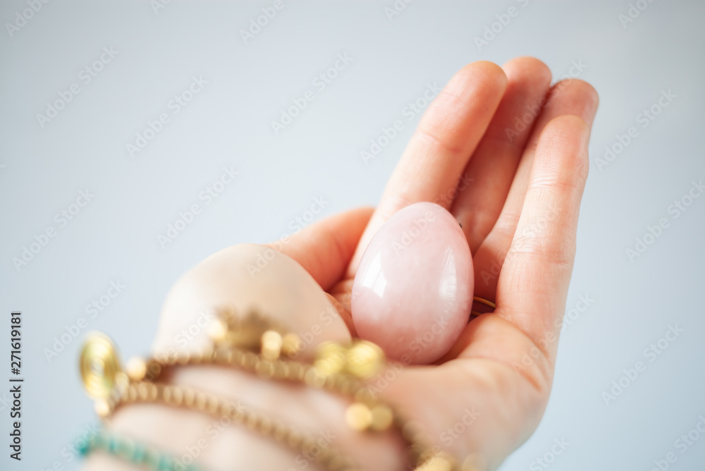 woman holding in hand a vaginal (yoni) egg. Rose quartz crystal jade egg. Copy space woman holding in hand a vaginal (yoni) egg. Rose quartz crystal jade egg. Copy space