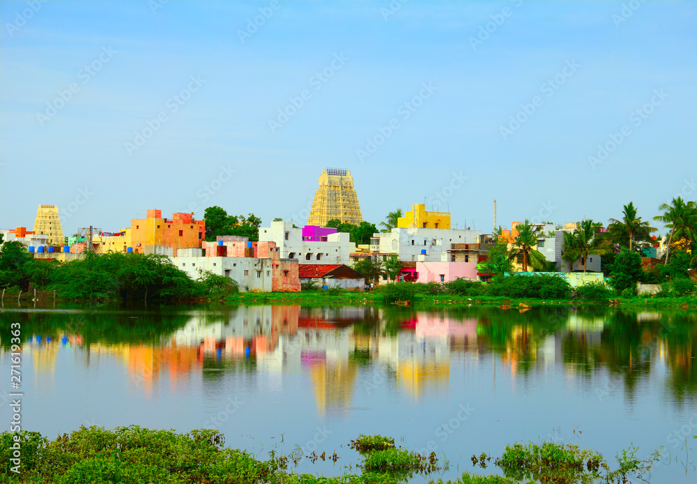 Obraz premium Beautiful scenic view of sacred city Kanchipuram (Kanchi) with colorful traditional houses, gopura of Hindu Temple bright foliage reflekted at calm lake waters, Tamil Nadu, South India