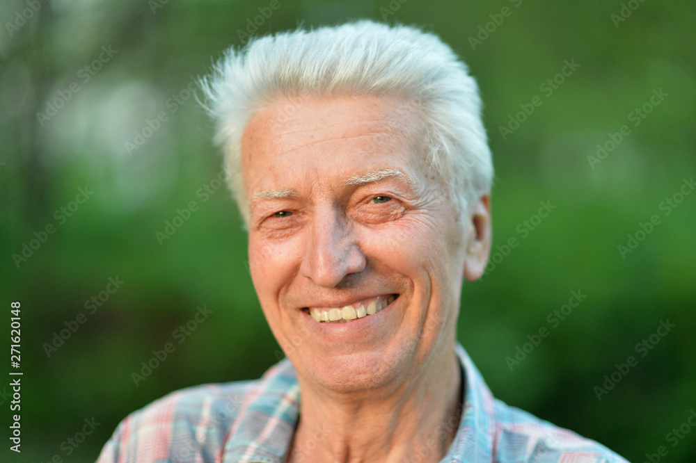 Smiling senior man posing in summer park Smiling senior man posing in summer park