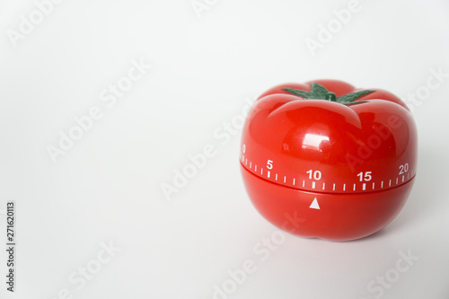 Close up view of mechanical tomato shaped kitchen clock timer for cooking & studying. Used for pomodoro technique for time and productivity management. Isolated on white background, set at 10 minutes. photo