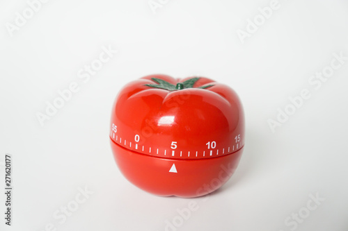 Close up view of mechanical tomato shaped kitchen clock timer for cooking & studying. Used for pomodoro technique for time and productivity management. Isolated on white background, set at 5 minutes.