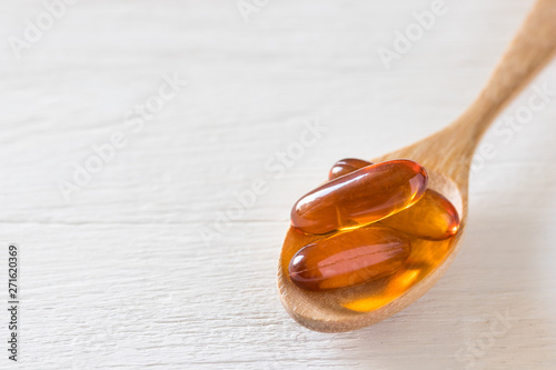 Close up view of fish oil capsule on white wooden background, vitamin and supplementa pill concept