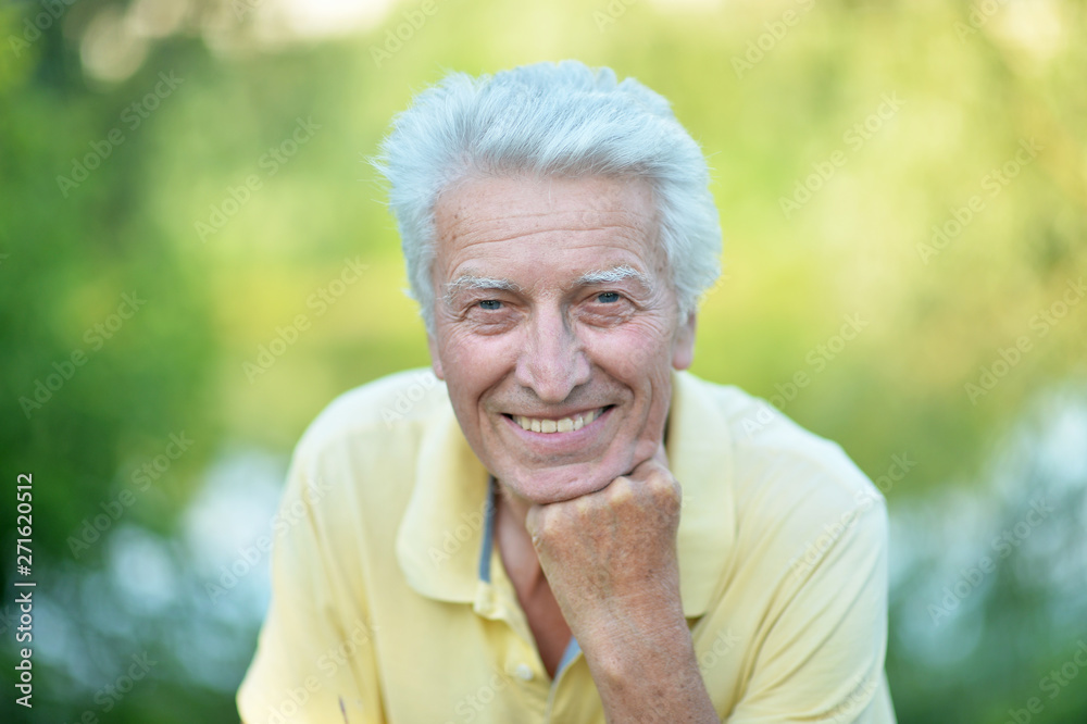 Smiling senior man posing in summer park Smiling senior man posing in summer park