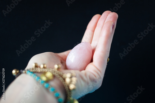 woman holding in hand a vaginal (yoni) egg. Rose quartz crystal jade egg. Copy space