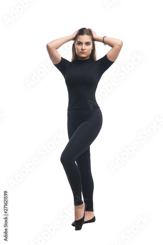 Slender brunette girl in black tight clothes standing isolated on white background.