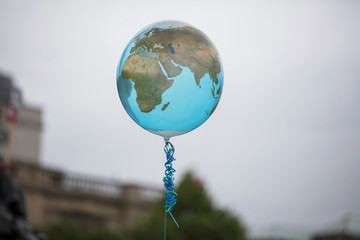 An earth shaped balloon floating on a string. Climate and environment concept
