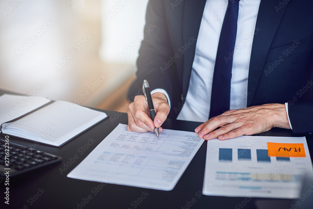 Businessman looking over documents while sitting at his office d Businessman looking over documents while sitting at his office d