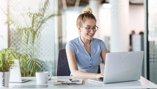 Young business woman working on laptop in office photo