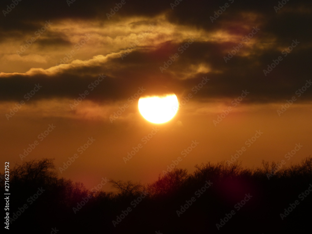 sun dipping below the clouds at sunset