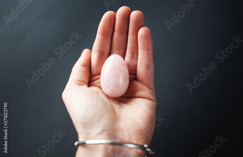 woman holding in hand a vaginal (yoni) egg. Rose quartz crystal jade egg. Copy space photo