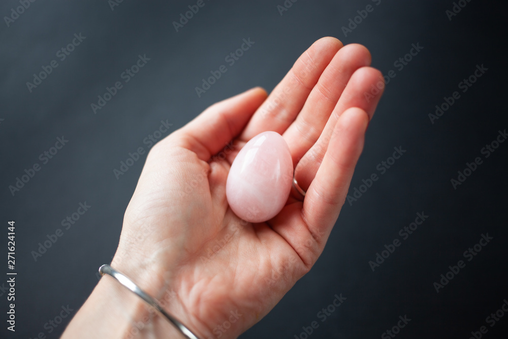 woman holding in hand a vaginal (yoni) egg. Rose quartz crystal jade egg. Copy space woman holding in hand a vaginal (yoni) egg. Rose quartz crystal jade egg. Copy space