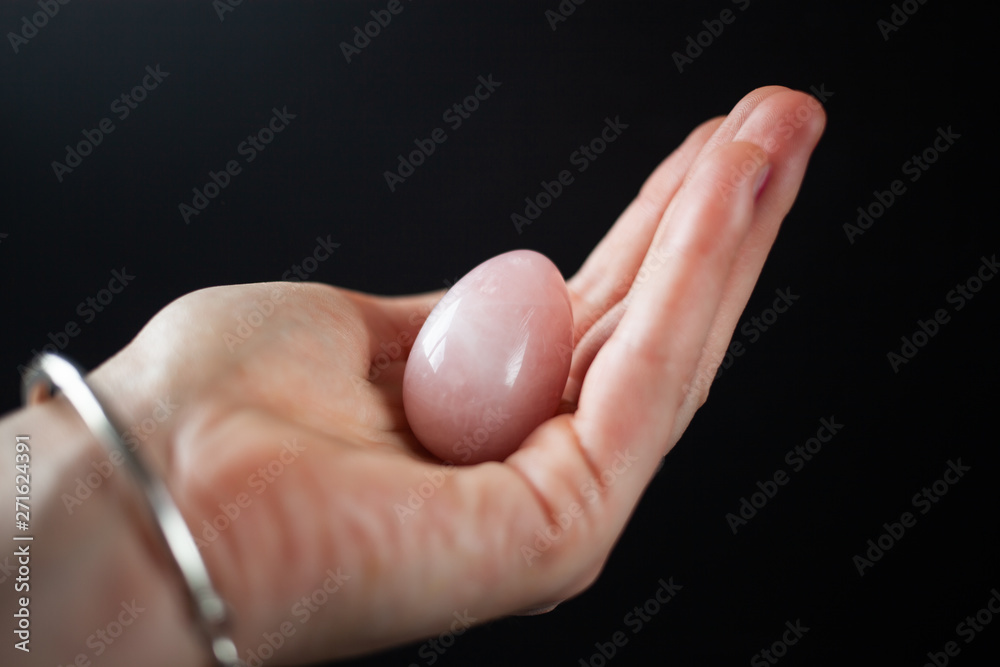woman holding in hand a vaginal (yoni) egg. Rose quartz crystal jade egg. Copy space woman holding in hand a vaginal (yoni) egg. Rose quartz crystal jade egg. Copy space