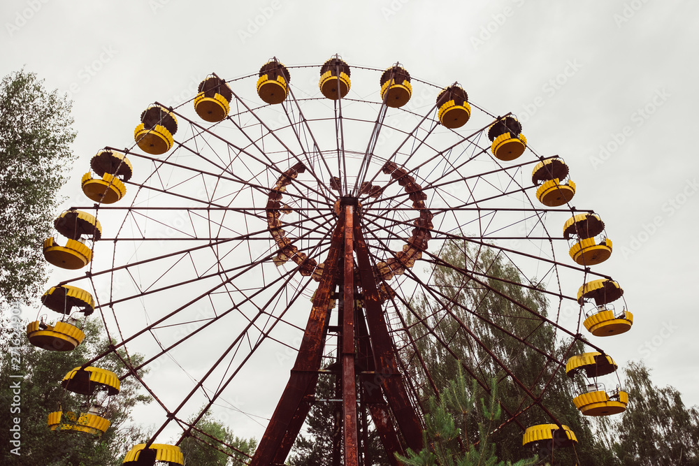 Destroyed abandoned ghost city Pripyat ruins after Chernobyl disaster. Old broken rusty metal yellow carousel wheel , amusement park. Exclusion zone, radiation risk, apocalyptic fallout lost town. Destroyed abandoned ghost city Pripyat ruins after Chernobyl disaster. Old broken rusty metal yellow carousel wheel , amusement park. Exclusion zone, radiation risk, apocalyptic fallout lost town.
