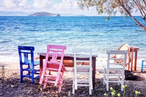 Four colorful wooden retro chairs and the table of an outdoor restaurant near the sea