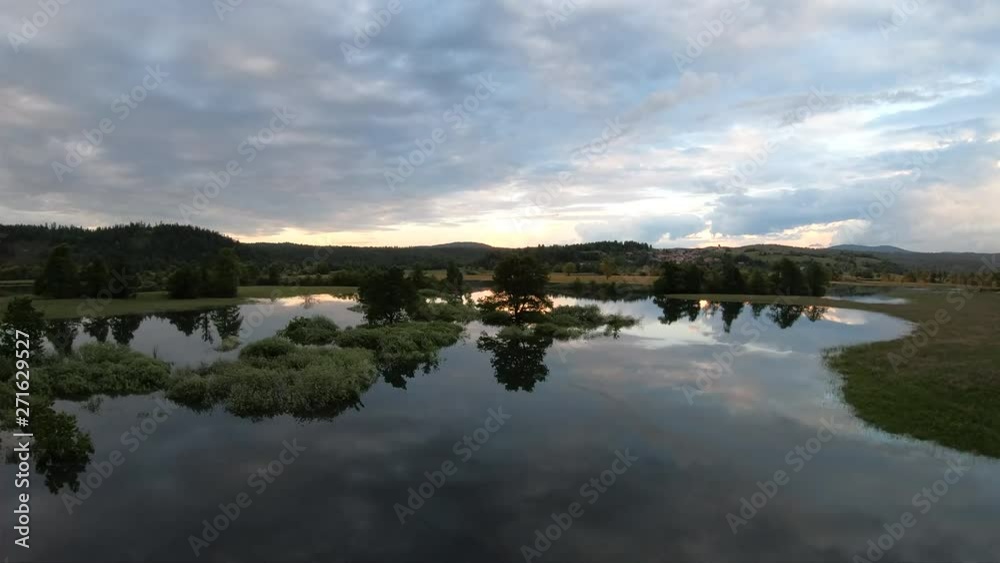 AERIAL Across the tranquil water in the valley after floods with sky reflecting on it at sunset AERIAL Across the tranquil water in the valley after floods with sky reflecting on it at sunset