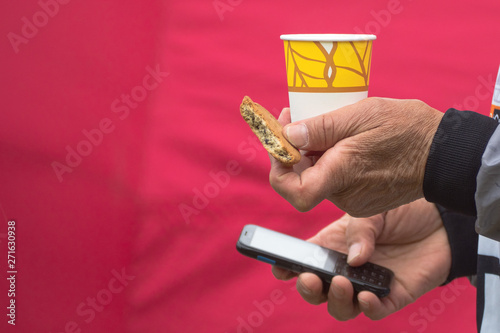 a man with a glass of tea, cookies and a phone on a red background