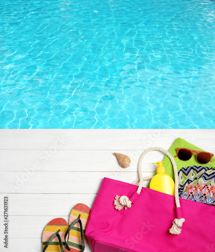 Flat lay composition with beach accessories on wooden pier near water, space for text