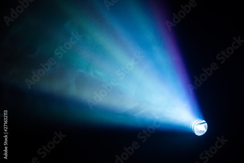 projector spotlight blue color , smoke texture background . light beam screening and glowing for movie cinema and film multimedia production in dark black room at night . wide lens showing, copy space