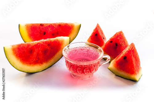 Detoxifying Watermelon seed's tea in a transparent glass cup along with watermelon pieces in triangle shape isolated on white.