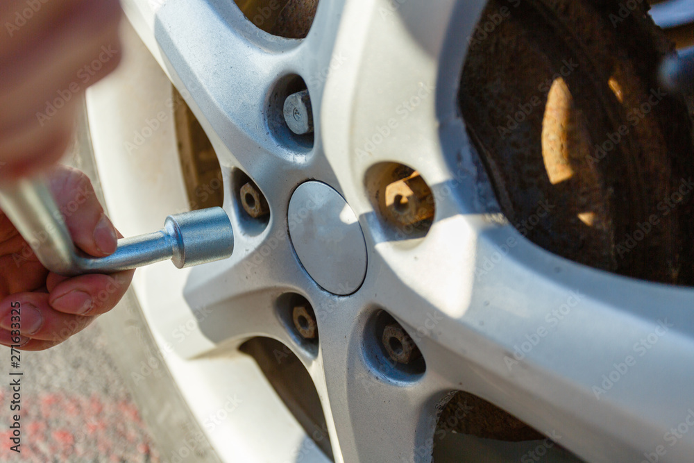 Closeup hands with cylinder wrench unscrew damaged wheel of car. Man