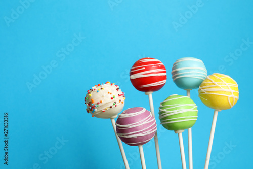 Many bright delicious cake pops on color background. Space for text